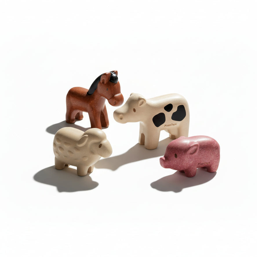 PlanToys farm animals set featuring colorful wooden cow, pig, sheep, and horse figures on a natural background.