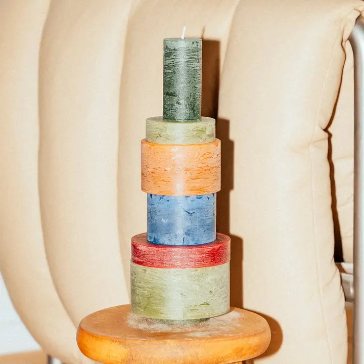 Stack of six modern Candl Stack 06 candles by Stan Editions in varying heights with white and neutral tones on a wooden surface.