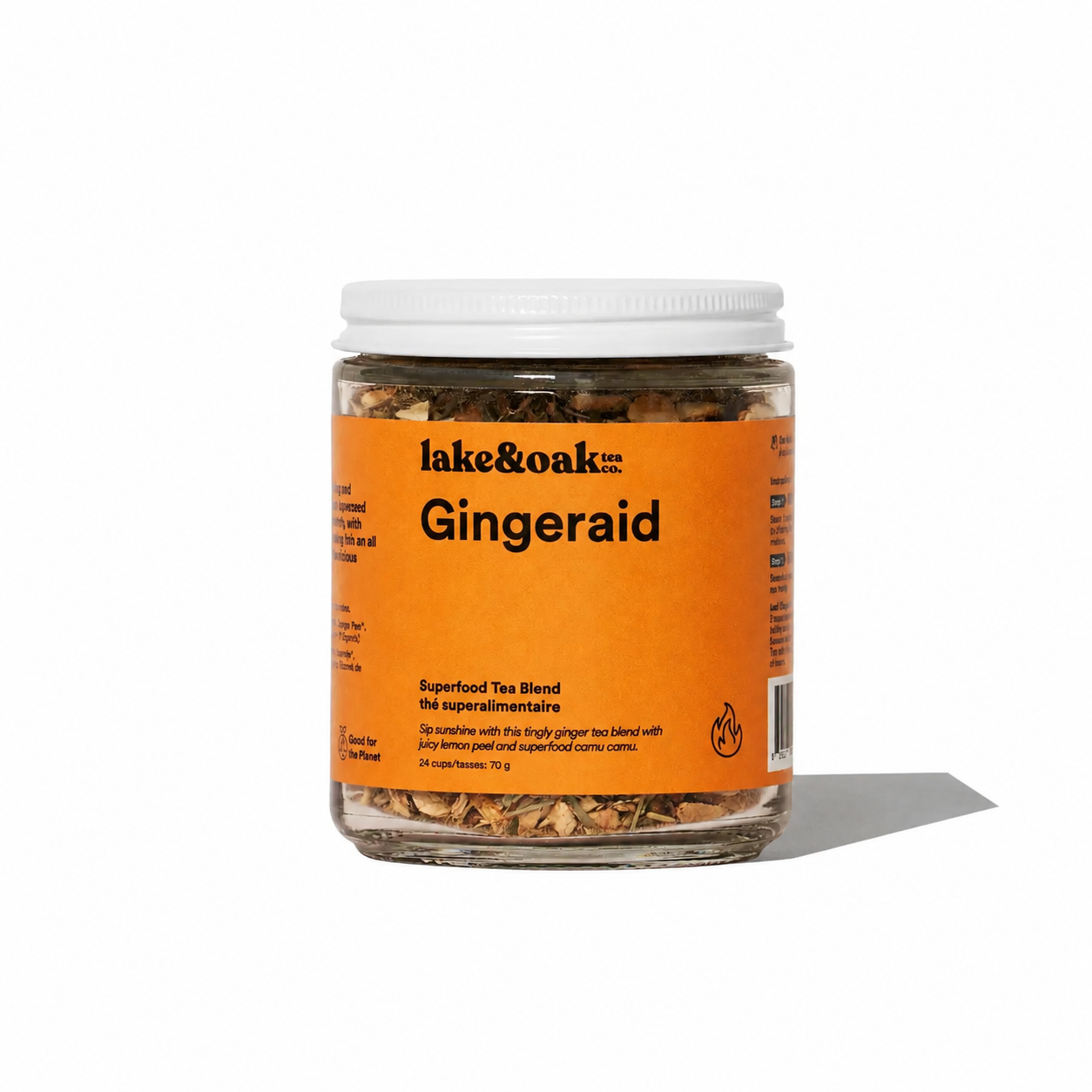 Cup of Lake & Oak Tea Co. Gingeraid herbal tea with fresh ginger slices in a clear glass mug on a wooden table.