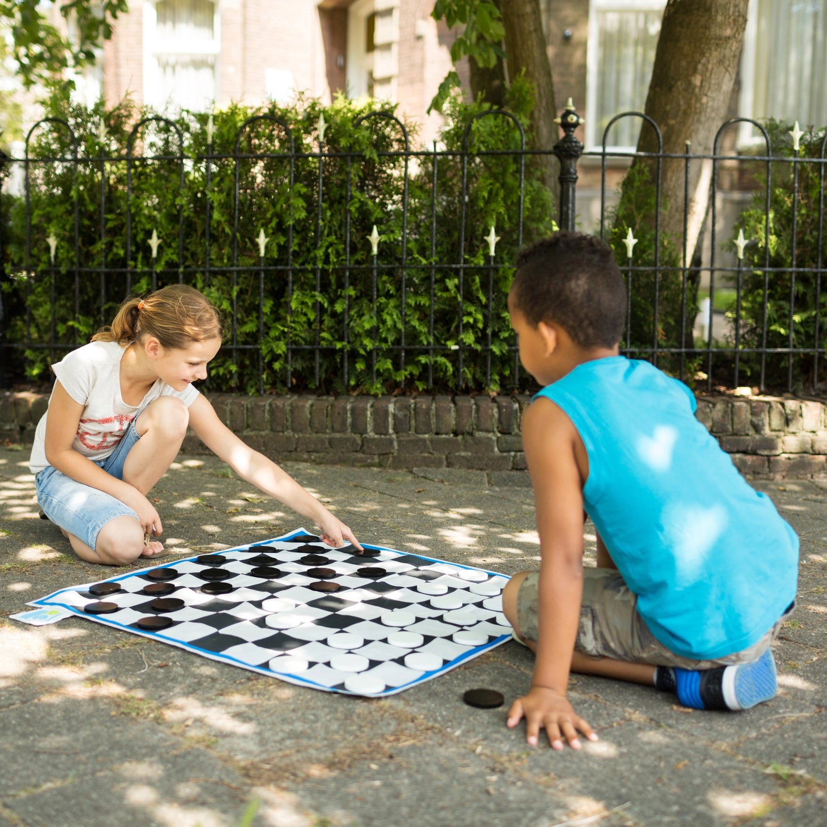 Checkers Play XL by BS Toys featuring a large wooden checkers board and red and black playing pieces on a smooth surface.