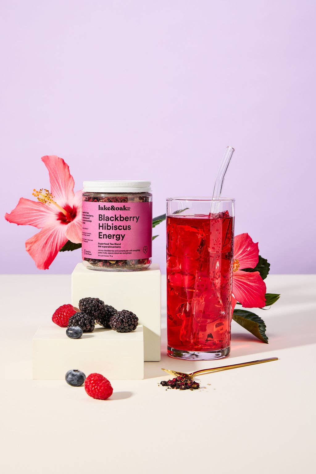 Blackberry Hibiscus tea by Lake & Oak Tea Co. in a glass cup with fresh blackberries and hibiscus flowers on a wooden table.