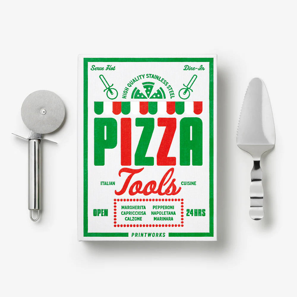 Printworks essential pizza tools gift set with pizza cutter, server, and peel, arranged on a wooden surface.