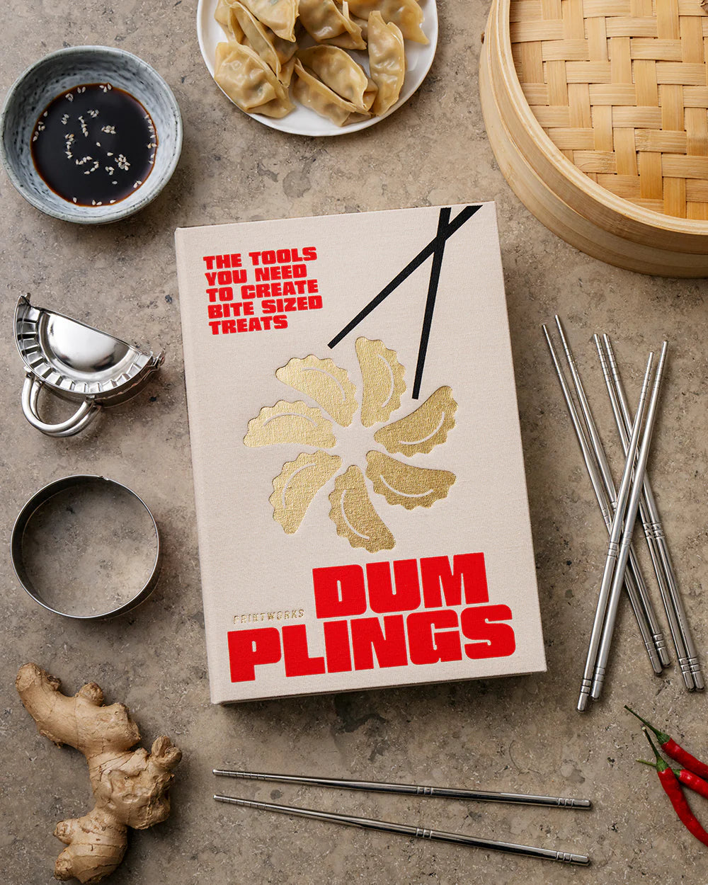 Printworks gift set of dumpling tools with various utensils for making and serving dumplings, arranged on a wooden surface.