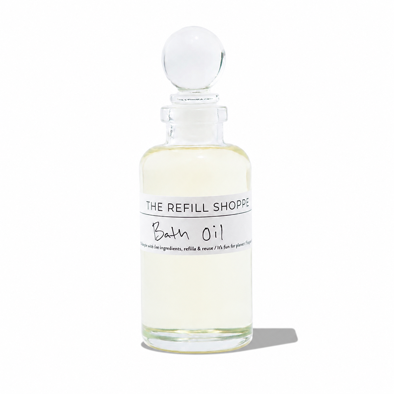 A bottle of The Refill Shoppe bath oil with a clear label, surrounded by relaxing spa elements on a white background.