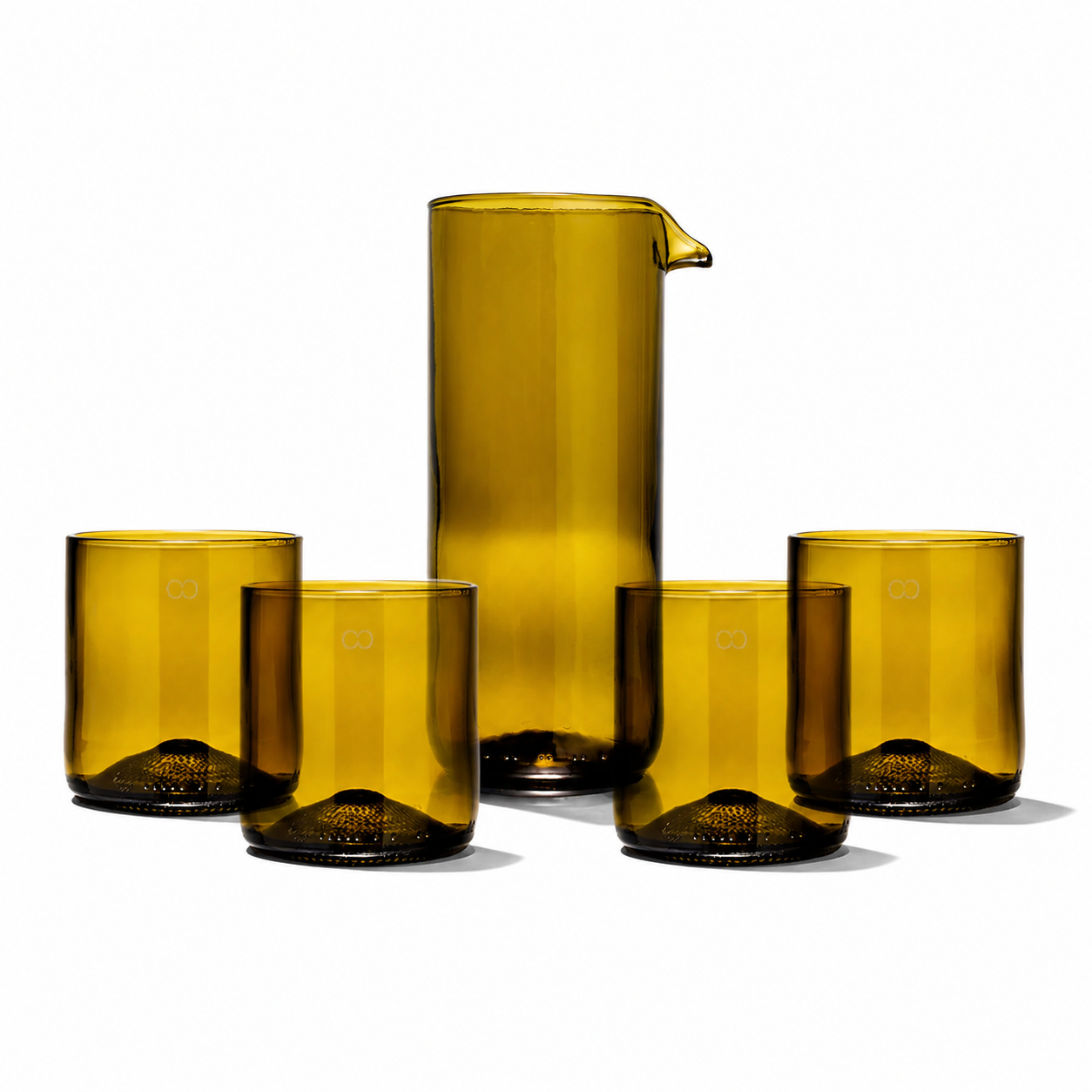 Rebottled glass carafe with four short tumblers, clear and elegant for serving beverages in a stylish, minimalist setting.