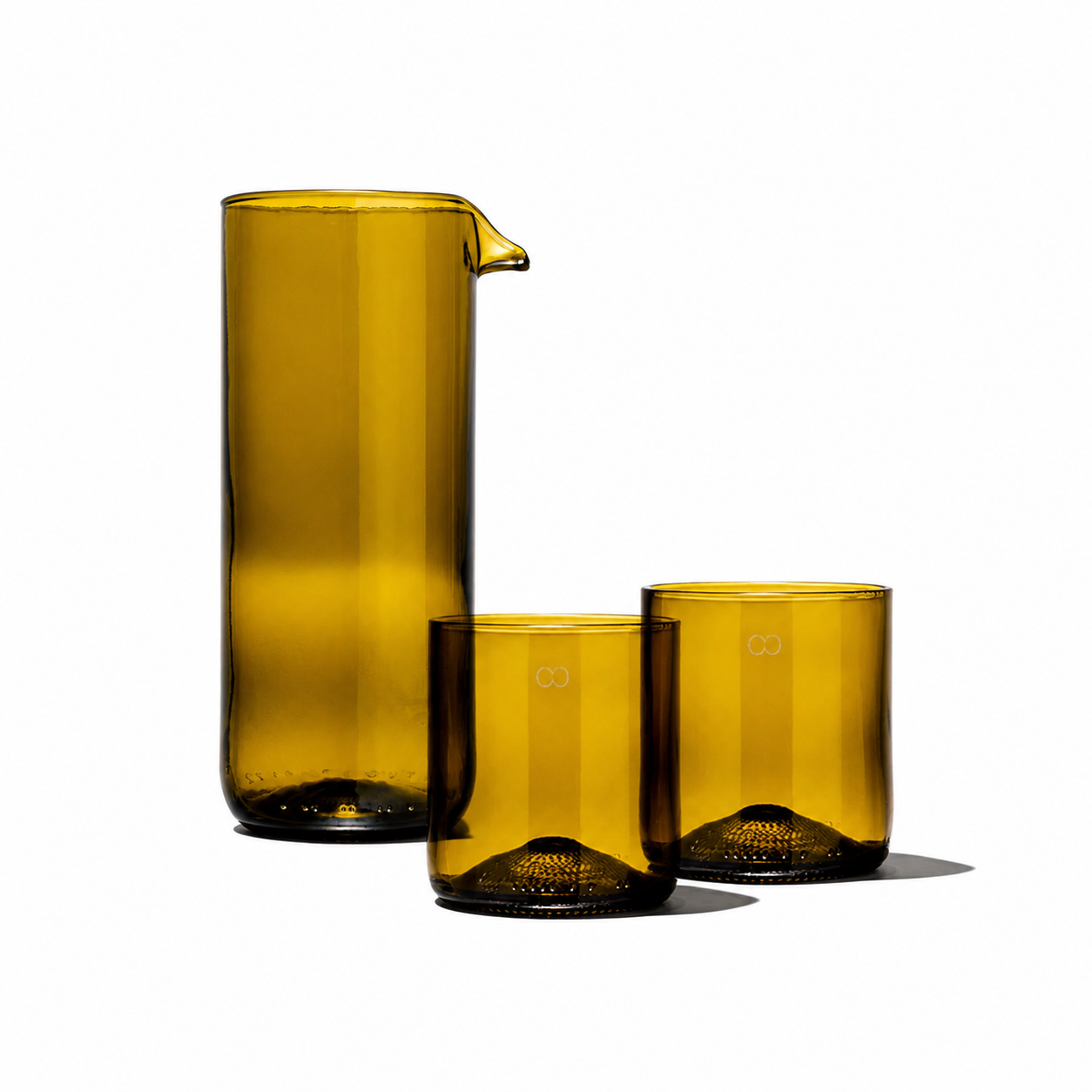 Rebottled glass carafe with two short tumblers on a wooden surface, showcasing elegant drinkware for serving beverages.