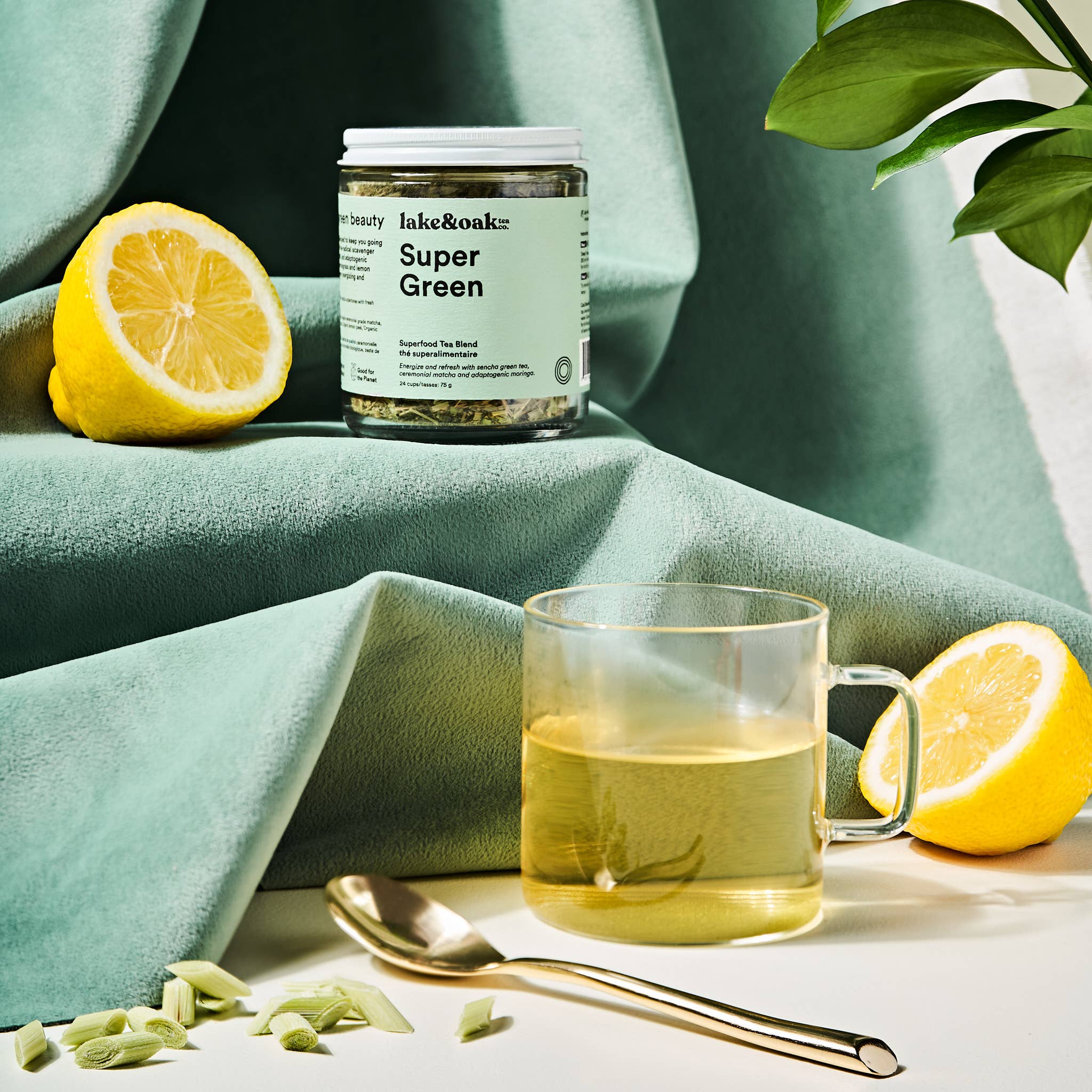 A cup of Super Green tea from Lake & Oak Tea Co. with vibrant green tea leaves and brewed tea in a white cup on a wooden surface.