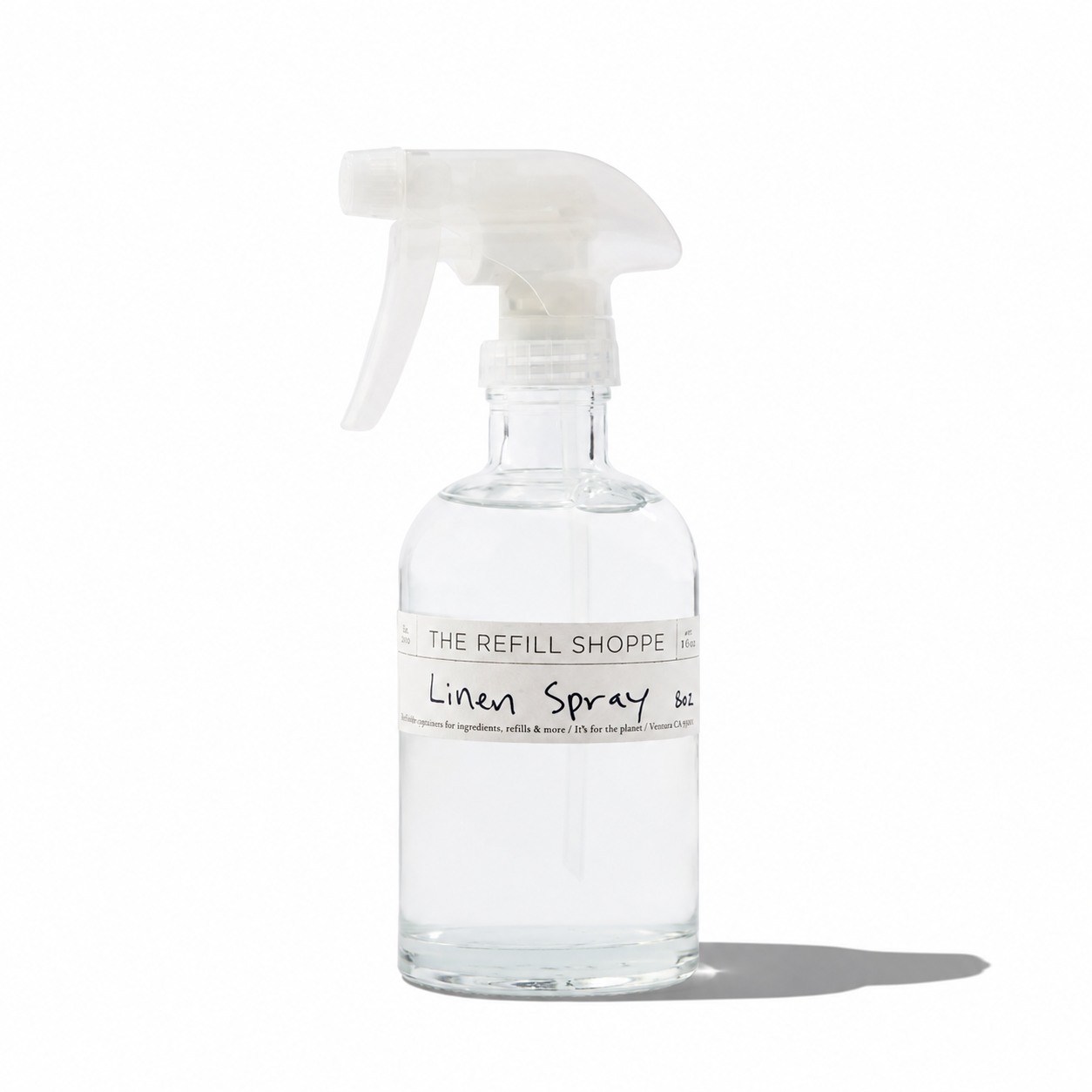A bottle of The Refill Shoppe linen spray with a floral design label, used for freshening fabrics and home textiles.
